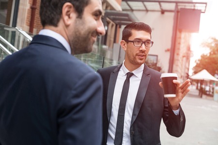 Two businessmen talking outdoors while taking coffee breakの写真素材