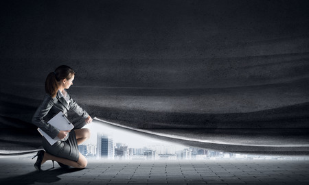 Young woman in business suit opening cement curtainの写真素材