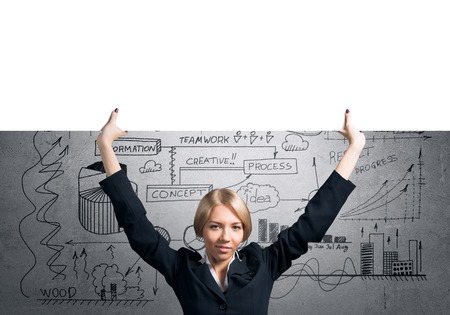 Portrait of blond businesswoman holding white blank banner above headの写真素材