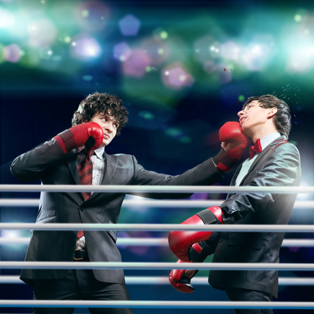Two businessman with boxing gloves in the ring fighting with each otherの写真素材