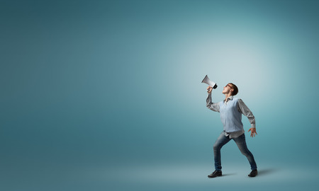 Teenager boy in glasses screaming emotional in megaphone