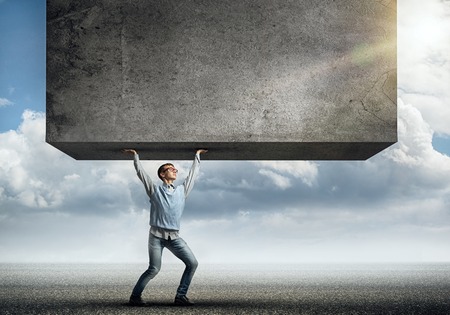 Teenager boy lifting stone wall above headの写真素材