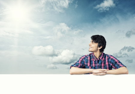 Portrait of young handsome man with blank bannerの写真素材