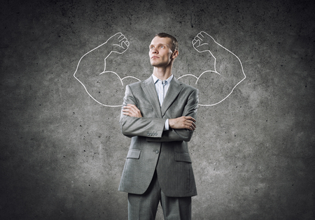 Businessman with strong arms drawn with chalk behind his backの写真素材