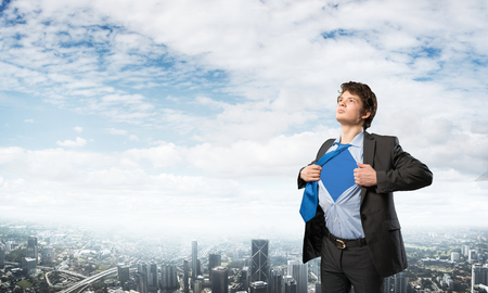 Office worker opening his shirt like superhero on modern city backgroundの写真素材