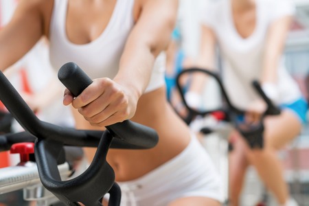 Small group of young people exercising on bikes in fitness centerの写真素材