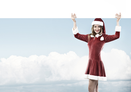 Full length of Christmas Santa girl holding white blank banner above headの写真素材