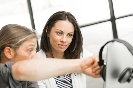 Young coworkers working together and discussing points while using computerの写真素材