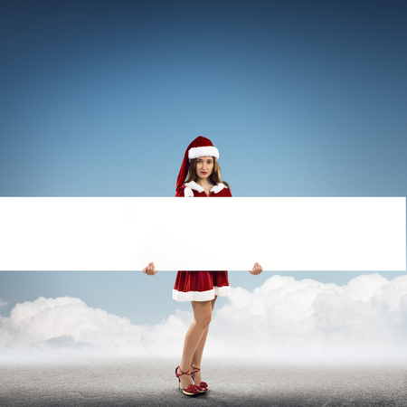 Full length of Christmas Santa girl holding white blank bannerの写真素材