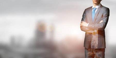 Close up of businessman with arms crossed on chest on modern city backgroundの写真素材