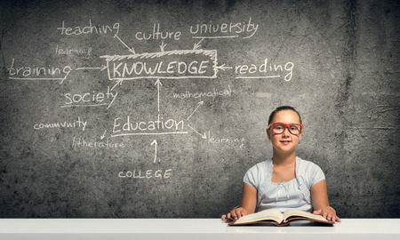 Cute school girl in red glasses playing pianoの写真素材