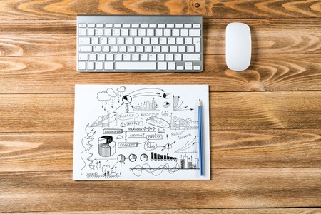 Top view of notepad with idea sketches keyboard and pencil on wooden tableの写真素材