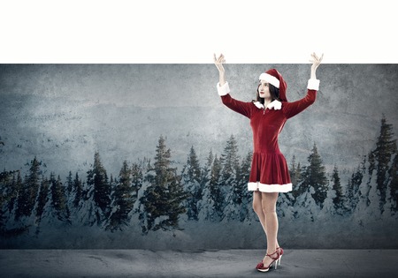 Full length of Christmas Santa girl holding white blank banner above headの写真素材