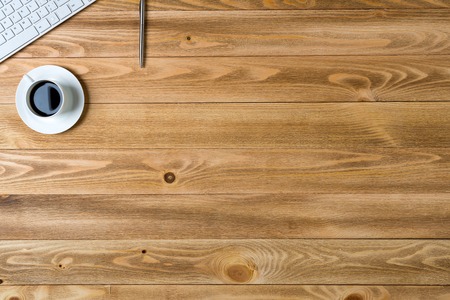 Top view of workplace with cup keyboard pencil on wooden table