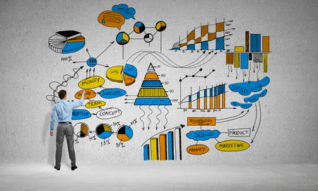 Businessman standing with back and drawing colorful business ideas on concrete wallの写真素材