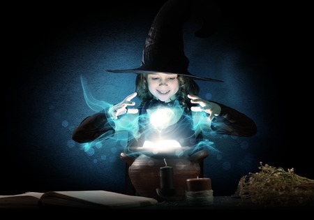 Little Halloween witch reading conjure from magic book above potの写真素材