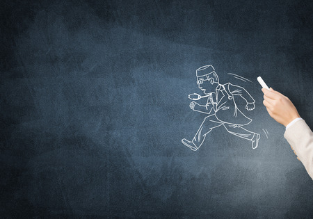 Female hand drawing with chalk doctor man on blackboardの写真素材