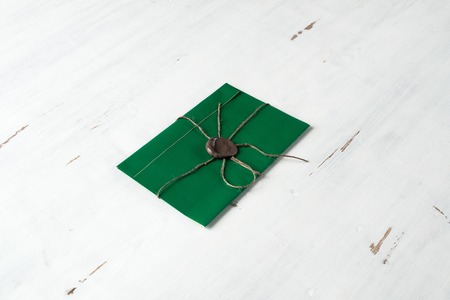 Green letter envelope with wax seal on wooden surface