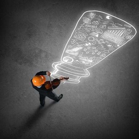Top view of engineer man playing violin and business strategy sketches on floorの写真素材