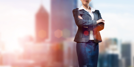Close up of businesswoman with arms crossed on chest on modern city backgroundの写真素材