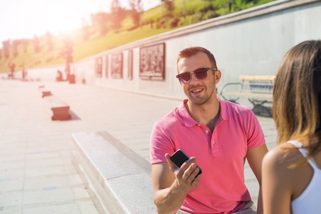 Young smiling couple in summer street using smartphoneの写真素材