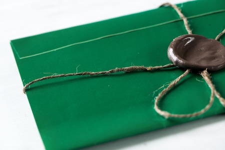 Green letter envelope with wax seal on wooden surfaceの写真素材