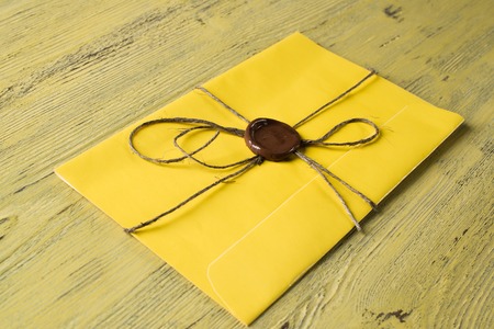 Yellow letter envelope with wax seal on wooden surface