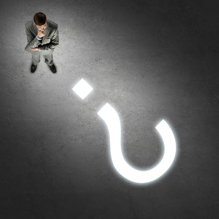 Top view of thoughtful businessman looking at glowing sign on concrete floorの写真素材
