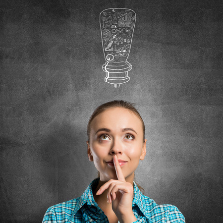 Portrait of attractive teenage girl with finger on lips on concrete backgroundの写真素材