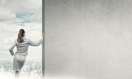 Confident businesswoman standing with back and leaning on cement blank wallの写真素材