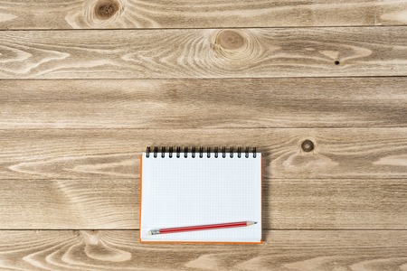Top view of blank notepad and pencil on wooden table