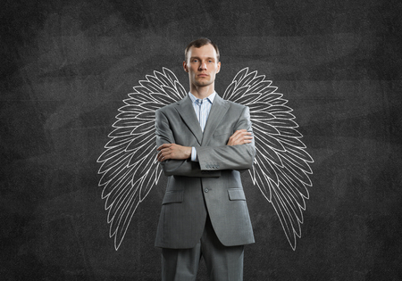 Young businessman with chalk drawn wings behind his backの写真素材