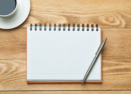 White blank notepad with cup of coffee on wooden tableの写真素材