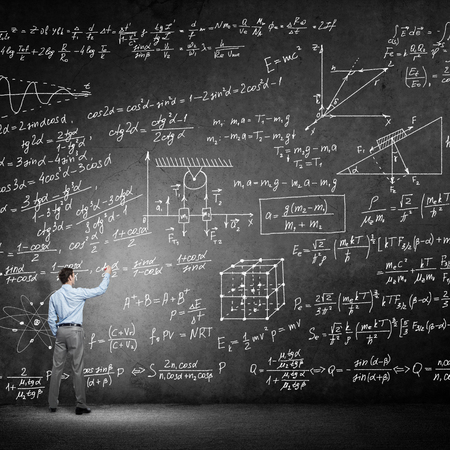 Rear view of man drawing formulas on blackboard with chalk