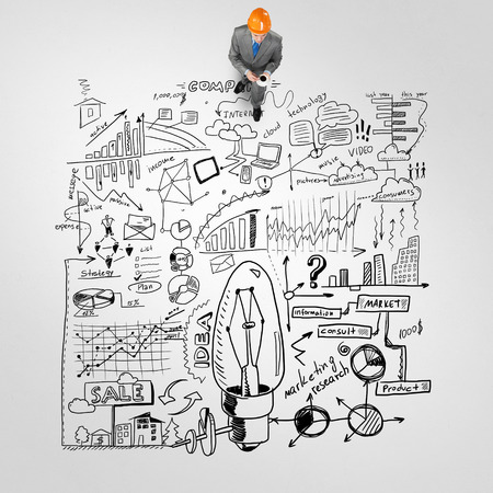 Top view of engineer man with coffee cup and business strategy sketches on floorの写真素材