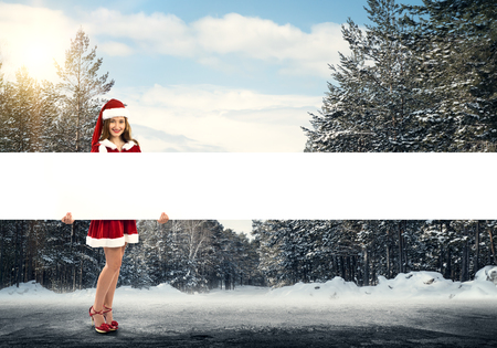 Full length of Christmas Santa girl holding white blank bannerの写真素材