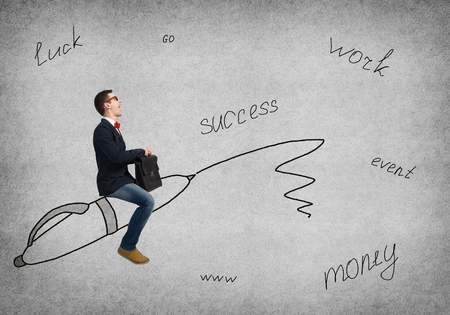 Young man in glasses riding drawn pen on concrete backgroundの写真素材