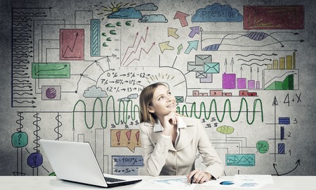 Pensive businesswoman with pen in hands thinking over her business planの写真素材