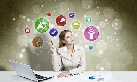 Elegant businesswoman at workplace and media icons at backgroundの写真素材