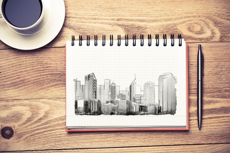 Wooden table with coffee cup and architectural sketches on notepadの写真素材