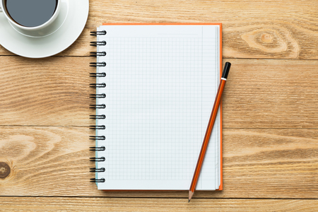White blank notepad with cup of coffee on wooden tableの写真素材