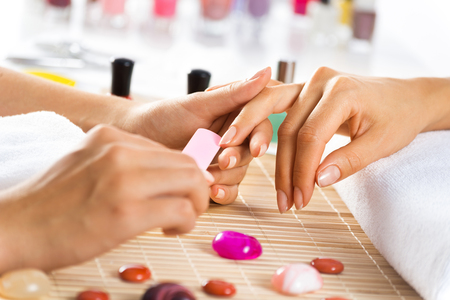 Woman in salon receiving manicure by nail beauticianの写真素材