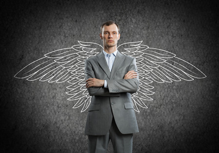 Young businessman with chalk drawn wings behind his backの写真素材