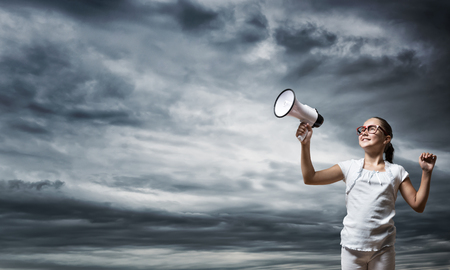 Girl of school age with megaphone on cloud backgroundの写真素材