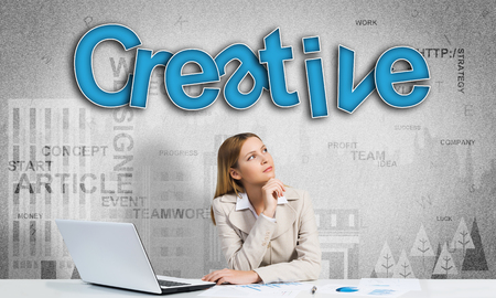 Attractive young businesswoman sitting at table and thinking over her ideaの写真素材