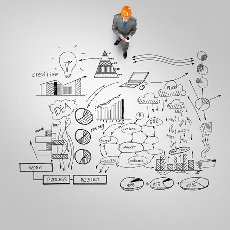 Top view of engineer man with coffee cup and business strategy sketches on floorの写真素材