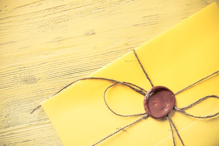 Yellow letter envelope with wax seal on wooden surfaceの写真素材
