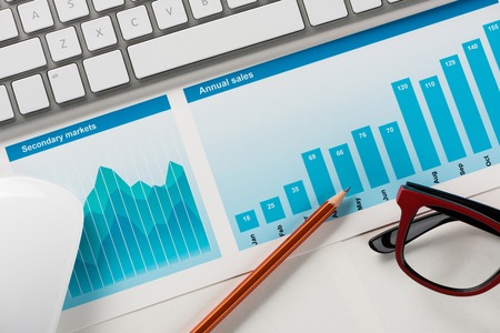 Business workplace with keyboard mouse and papers with graphs and diagrams