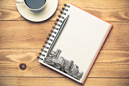 Wooden table with coffee cup and architectural sketches on notepadの写真素材