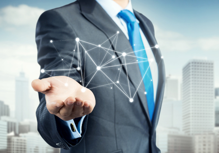 Businessman hand showing digital connection lines on city landscapeの写真素材